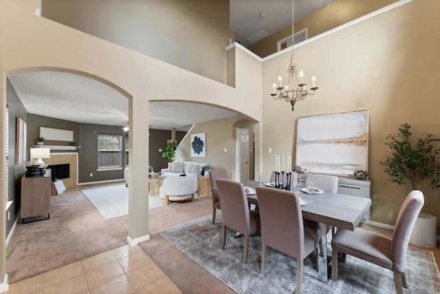 28210 Slatestone Ln, Spring, TX 77386 - dining room featuring light carpet, arched walkways, light tile patterned flooring, a tile fireplace, and a high ceiling