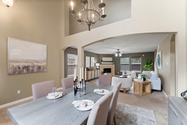 28210 Slatestone Ln, Spring, TX 77386 - dining room featuring arched walkways, a tile fireplace, a ceiling fan, a chandelier, and light colored carpet