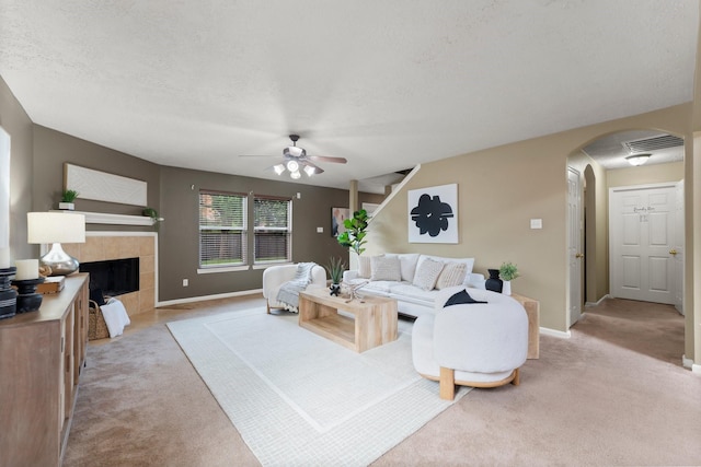 28210 Slatestone Ln, Spring, TX 77386 - living area featuring light colored carpet, arched walkways, a ceiling fan, a tile fireplace, and a textured ceiling