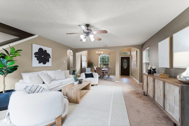 28210 Slatestone Ln, Spring, TX 77386 - living room featuring arched walkways, a ceiling fan, a chandelier, light carpet, and a textured ceiling