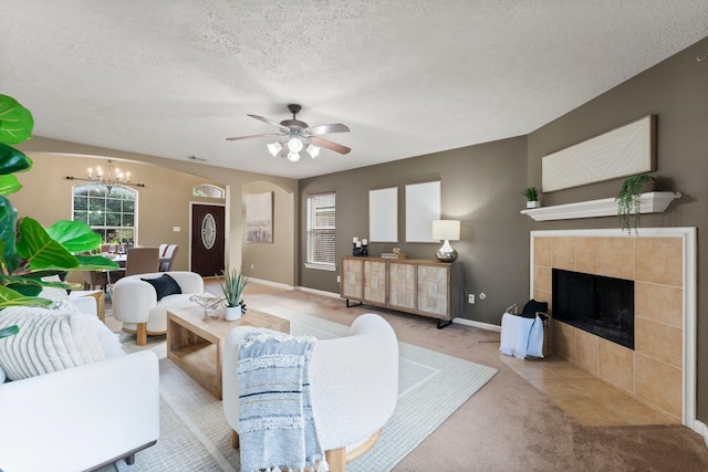 28210 Slatestone Ln, Spring, TX 77386 - carpeted living room with a chandelier, ceiling fan, a fireplace, a textured ceiling, and arched walkways