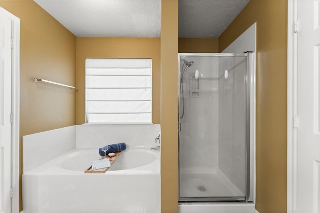 28210 Slatestone Ln, Spring, TX 77386 - bathroom featuring a stall shower, a bath, and a textured ceiling