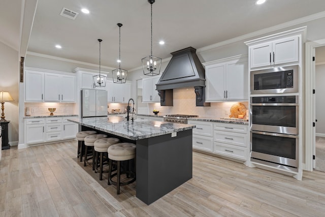 206 Rim Rock Rd, Huntsville, TX 77340 - kitchen featuring premium range hood, appliances with stainless steel finishes, a kitchen bar, light wood-style floors, and recessed lighting