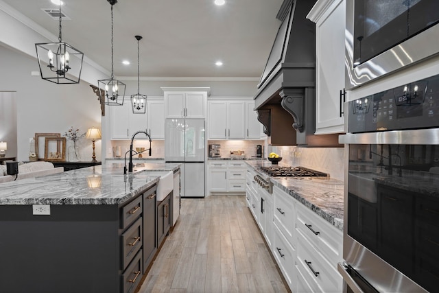 206 Rim Rock Rd, Huntsville, TX 77340 - kitchen featuring stainless steel appliances, a chandelier, decorative backsplash, white cabinets, and light wood finished floors