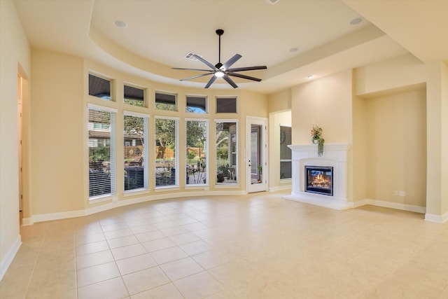 2728 Long Lasso Pass, Leander, TX 78641 - unfurnished living room with a tray ceiling, a ceiling fan, a glass covered fireplace, light tile patterned floors, and recessed lighting
