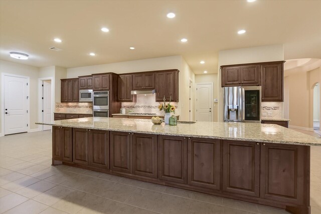 2728 Long Lasso Pass, Leander, TX 78641 - kitchen featuring appliances with stainless steel finishes, arched walkways, backsplash, a large island, and recessed lighting