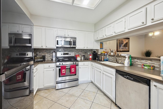 3907 Moss Tree Rd, Houston, TX 77043 - kitchen with stainless steel appliances, light tile patterned flooring, decorative backsplash, and white cabinets