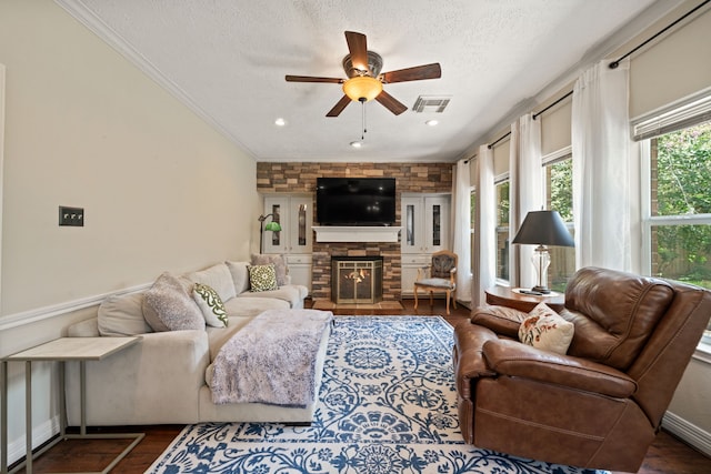 16447 Flint Run Way, Sugar Land, TX 77498 - living room with ceiling fan, a textured ceiling, dark wood-style flooring, a stone fireplace, and crown molding