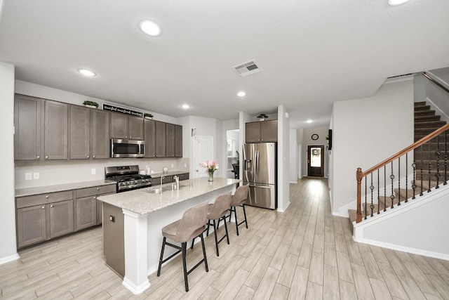 5206 Wyatt James Ln, Brookshire, TX 77423 - kitchen with stainless steel appliances, light wood-style floors, a kitchen breakfast bar, an island with sink, and recessed lighting