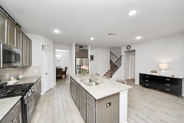 5206 Wyatt James Ln, Brookshire, TX 77423 - kitchen with appliances with stainless steel finishes, a center island with sink, light wood-style floors, light stone counters, and recessed lighting