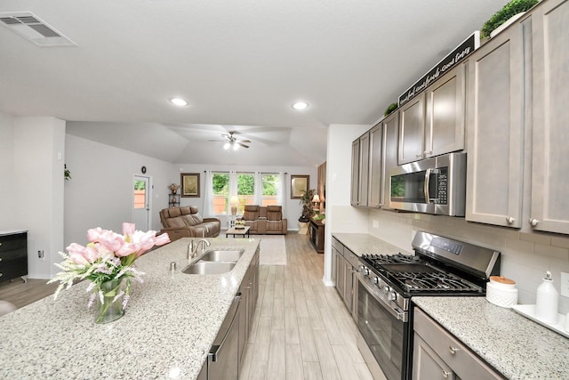 5206 Wyatt James Ln, Brookshire, TX 77423 - kitchen with appliances with stainless steel finishes, a ceiling fan, open floor plan, backsplash, and light wood-style flooring