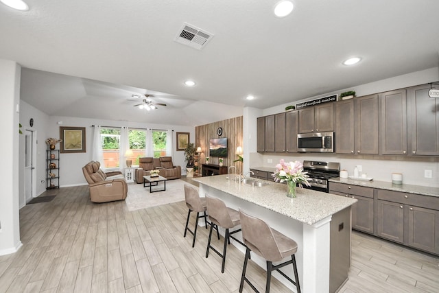 5206 Wyatt James Ln, Brookshire, TX 77423 - kitchen featuring appliances with stainless steel finishes, light wood-style floors, a ceiling fan, a kitchen breakfast bar, and open floor plan