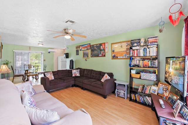 15050 Groveshire St, Channelview, TX 77530 - living area with wood finished floors, a ceiling fan, a textured ceiling, and an AC wall unit