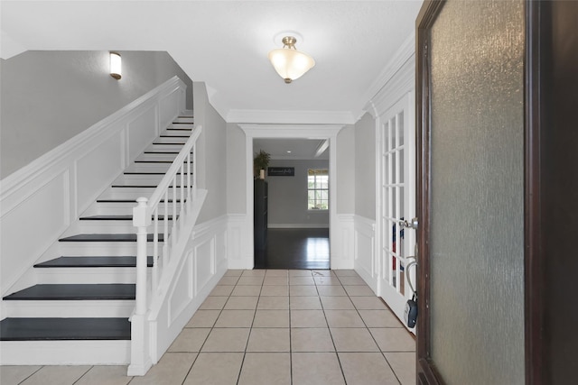 7403 Theisswood Rd, Spring, TX 77379 - entryway with a decorative wall, stairway, a wainscoted wall, light tile patterned floors, and crown molding