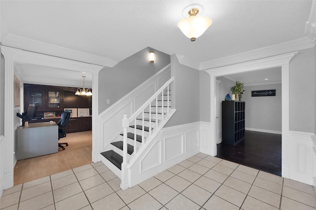 7403 Theisswood Rd, Spring, TX 77379 - stairs with tile patterned floors, a wainscoted wall, a decorative wall, crown molding, and a chandelier