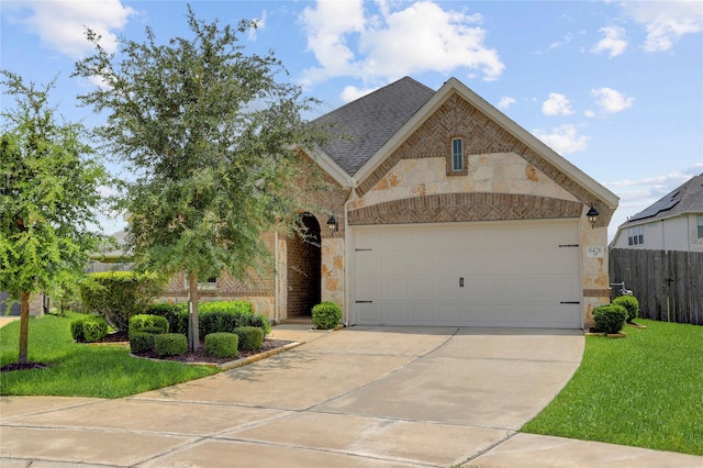 8426 Kari Bend Cir, Richmond, TX 77407 - french country inspired facade with concrete driveway, a garage, stone siding, brick siding, and roof with shingles