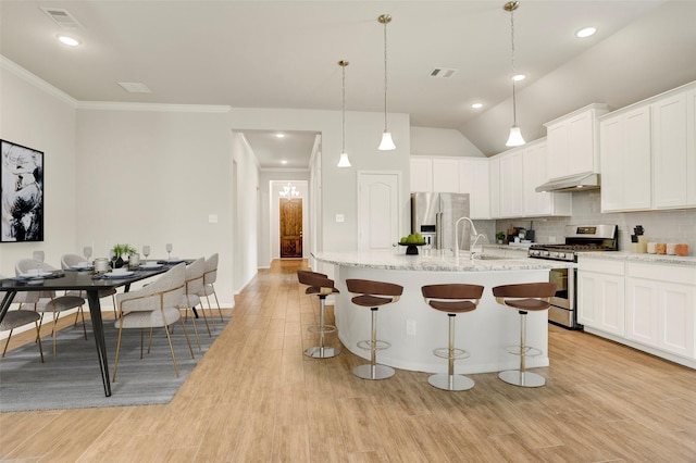 8426 Kari Bend Cir, Richmond, TX 77407 - kitchen featuring appliances with stainless steel finishes, a breakfast bar area, backsplash, light wood-style flooring, and white cabinets