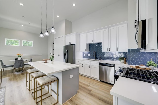 846 Elkhart St Unit B, Houston, TX 77091 - kitchen featuring appliances with stainless steel finishes, a center island, white cabinets, decorative backsplash, and light countertops