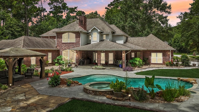 10530 Clubhouse Cir, Magnolia, TX 77354 - rear view of house featuring a gazebo, brick siding, a shingled roof, a patio area, and a chimney