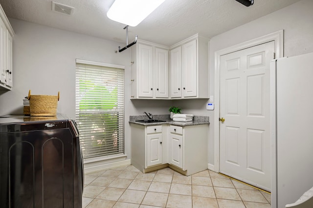 10530 Clubhouse Cir, Magnolia, TX 77354 - laundry room with washer / dryer, cabinet space, light tile patterned floors, and a textured ceiling