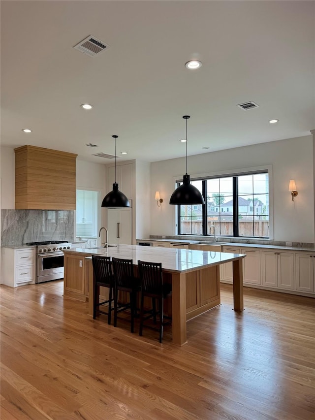 1701 Bayram Dr, Houston, TX 77055 - kitchen with high end stove, a large island, decorative backsplash, recessed lighting, and light wood-style floors