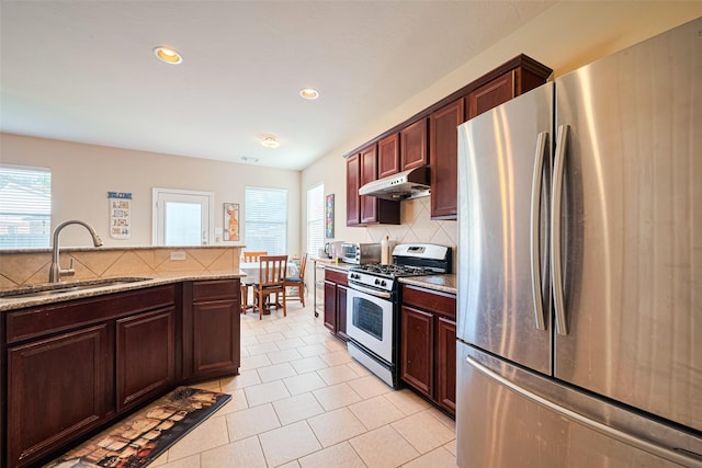 19914 Pemetic Trl, Richmond, TX 77407 - kitchen with stainless steel appliances, under cabinet range hood, tasteful backsplash, light stone counters, and light tile patterned floors