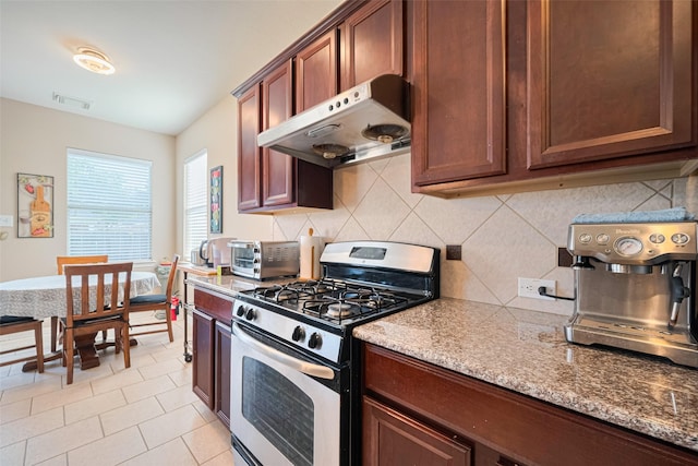 19914 Pemetic Trl, Richmond, TX 77407 - kitchen featuring gas stove, under cabinet range hood, backsplash, and light stone counters