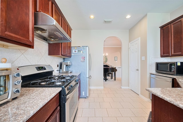 19914 Pemetic Trl, Richmond, TX 77407 - kitchen with appliances with stainless steel finishes, ventilation hood, arched walkways, decorative backsplash, and light countertops
