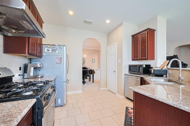 19914 Pemetic Trl, Richmond, TX 77407 - kitchen featuring stainless steel appliances, ventilation hood, arched walkways, backsplash, and light stone countertops