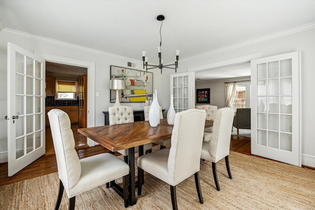 1656 Norfolk St, Houston, TX 77006 - dining space with a chandelier, crown molding, light wood-style floors, plenty of natural light, and french doors