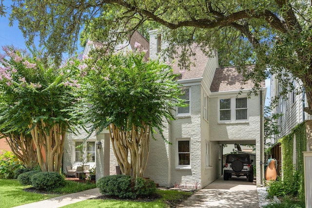 1656 Norfolk St, Houston, TX 77006 - view of property hidden behind natural elements featuring brick siding, a shingled roof, concrete driveway, and a carport