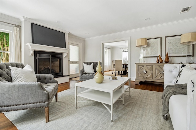 1656 Norfolk St, Houston, TX 77006 - living room featuring wood finished floors, plenty of natural light, crown molding, a fireplace with raised hearth, and a chandelier