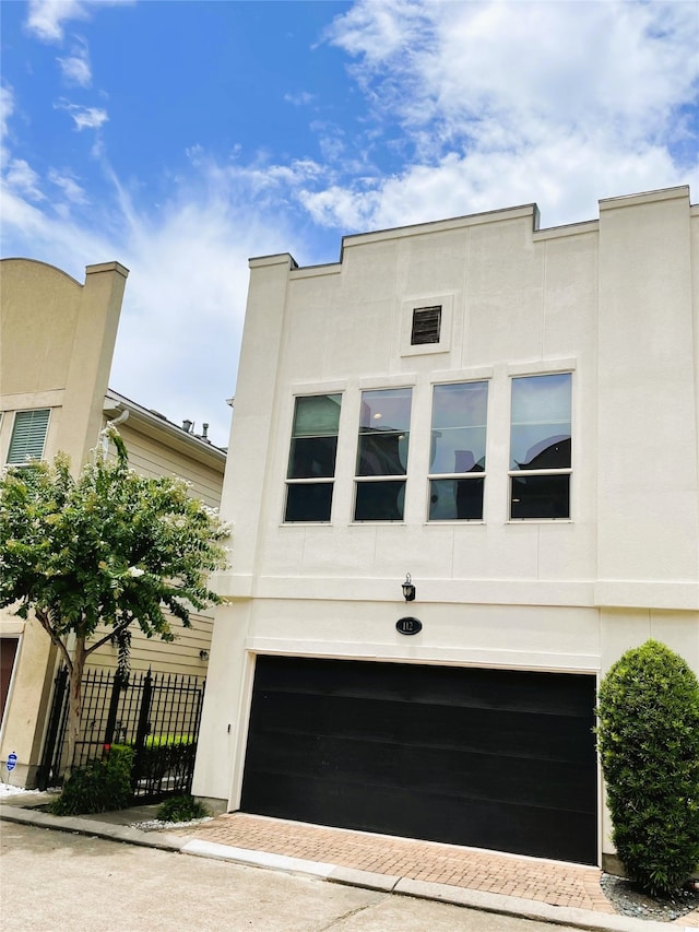 112 Riley Ln, Houston, TX 77003 - view of front of home with an attached garage, stucco siding, and decorative driveway