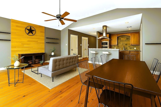 112 Riley Ln, Houston, TX 77003 - dining area featuring a fireplace, lofted ceiling, a ceiling fan, and light wood-type flooring