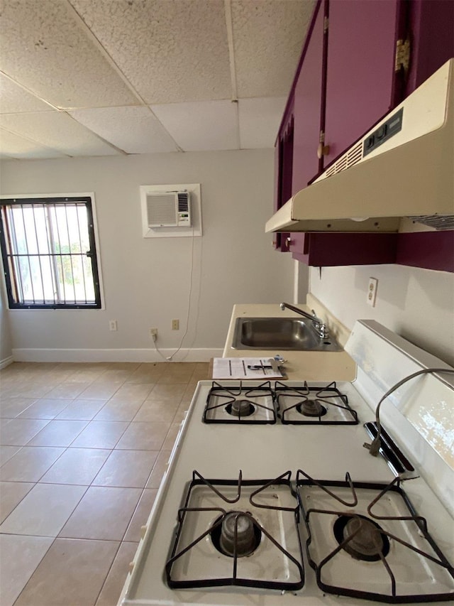 2705 Beatty St, Houston, TX 77023 - kitchen featuring under cabinet range hood, white gas stove, an AC wall unit, a paneled ceiling, and light tile patterned flooring