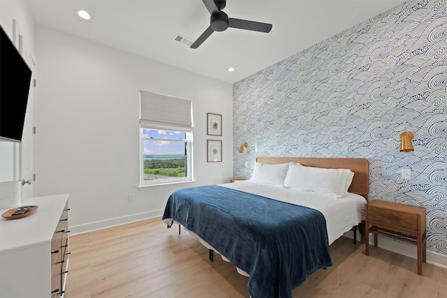 3430 Indian Beach Dr, Galveston, TX 77554 - bedroom with wallpapered walls, an accent wall, light wood finished floors, recessed lighting, and ceiling fan