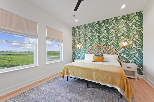 3430 Indian Beach Dr, Galveston, TX 77554 - bedroom featuring an accent wall, wallpapered walls, light wood-type flooring, recessed lighting, and ceiling fan