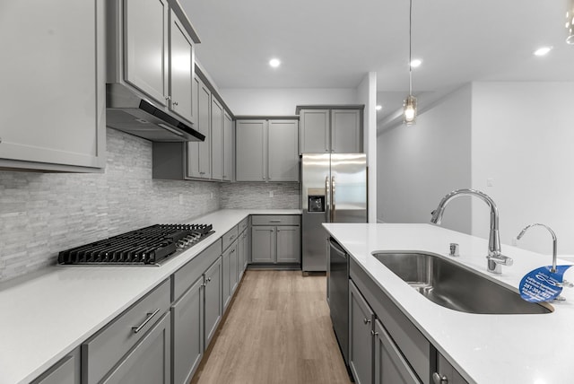 21410 Flora Springs Ln, Magnolia, TX 77355 - kitchen featuring under cabinet range hood, appliances with stainless steel finishes, gray cabinets, tasteful backsplash, and recessed lighting