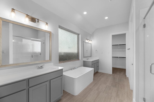 21410 Flora Springs Ln, Magnolia, TX 77355 - bathroom featuring a stall shower, two vanities, a bathtub, recessed lighting, and a walk in closet