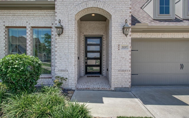 20207 Noble Arabian Dr, Tomball, TX 77377 - property entrance with brick siding, a garage, concrete driveway, and a shingled roof