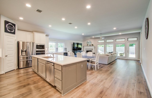 20207 Noble Arabian Dr, Tomball, TX 77377 - kitchen featuring stainless steel appliances, light wood-type flooring, recessed lighting, open floor plan, and a fireplace