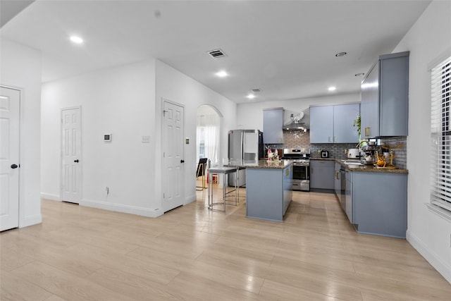 13206 Blass Ct, Houston, TX 77044 - kitchen featuring appliances with stainless steel finishes, a kitchen island, arched walkways, tasteful backsplash, and a breakfast bar area