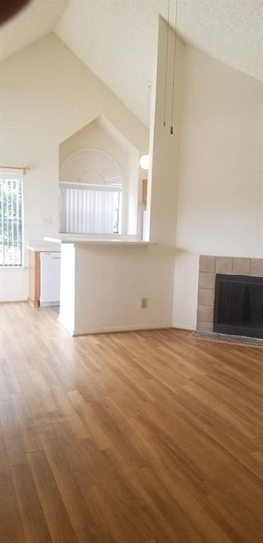 2300 Old Spanish Trl Unit 2116, Houston, TX 77054 - unfurnished living room featuring wood finished floors, a tile fireplace, and high vaulted ceiling
