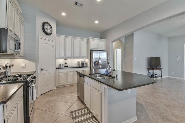 8922 Pinenut Dr, Cypress, TX 77433 - kitchen with stainless steel appliances, dark countertops, arched walkways, a center island with sink, and recessed lighting
