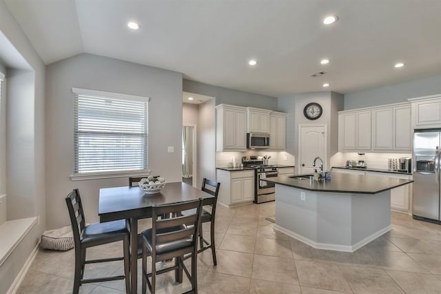 8922 Pinenut Dr, Cypress, TX 77433 - kitchen featuring stainless steel appliances, dark countertops, a center island with sink, recessed lighting, and light tile patterned floors