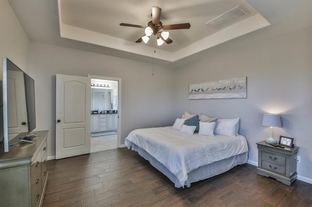 8922 Pinenut Dr, Cypress, TX 77433 - bedroom featuring a raised ceiling, dark wood-style floors, ensuite bath, and ceiling fan