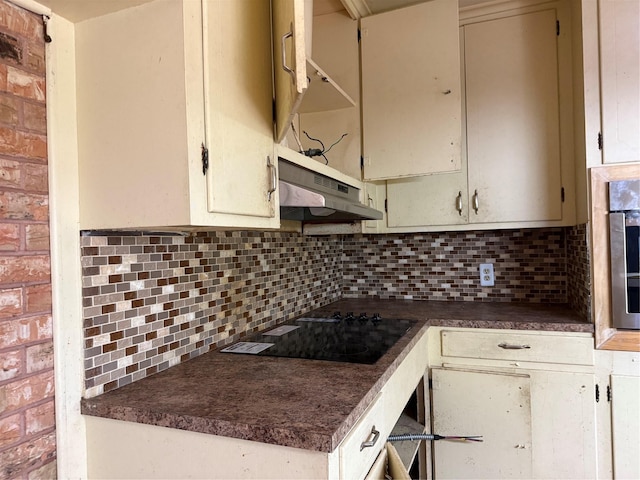 200 Cunningham Dr, Lufkin, TX 75901 - kitchen featuring under cabinet range hood, black electric cooktop, dark countertops, decorative backsplash, and cream cabinets