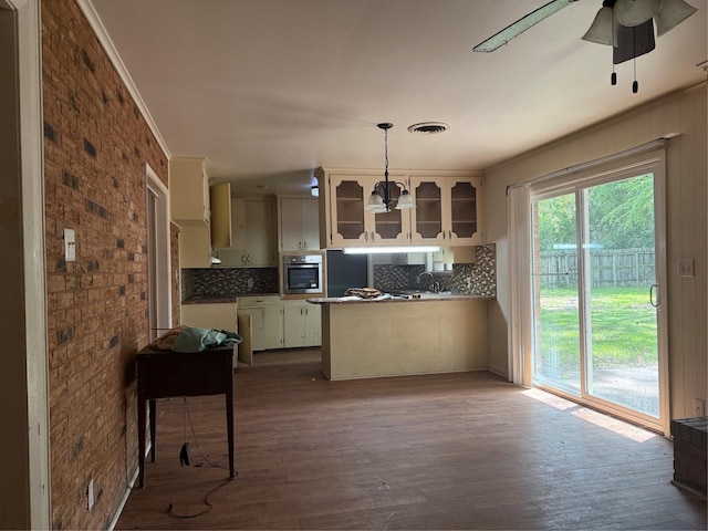 200 Cunningham Dr, Lufkin, TX 75901 - kitchen featuring oven, a peninsula, decorative backsplash, glass insert cabinets, and brick wall