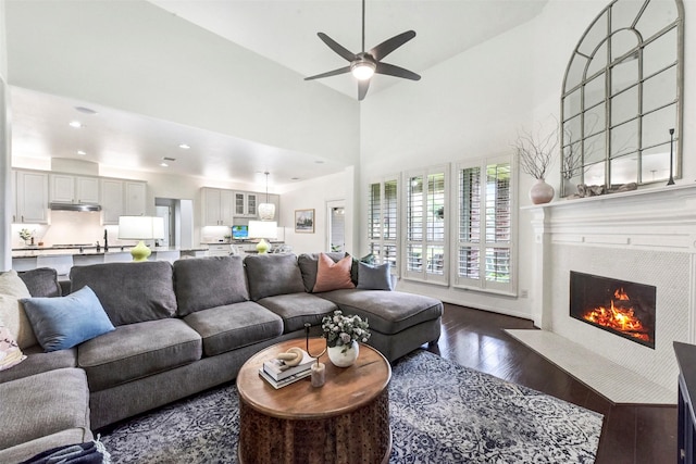 23706 Tristan Bay Ct, Spring, TX 77386 - living room with dark wood-style floors, ceiling fan, a fireplace, a high ceiling, and recessed lighting