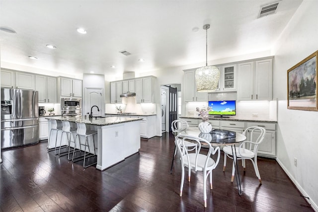 23706 Tristan Bay Ct, Spring, TX 77386 - kitchen featuring stainless steel appliances, a kitchen bar, a center island with sink, light stone countertops, and tasteful backsplash